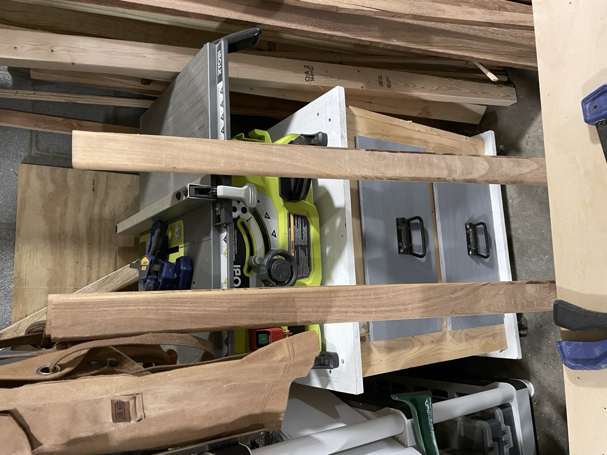 Teak slats ripped to width, standing on end beside a table saw