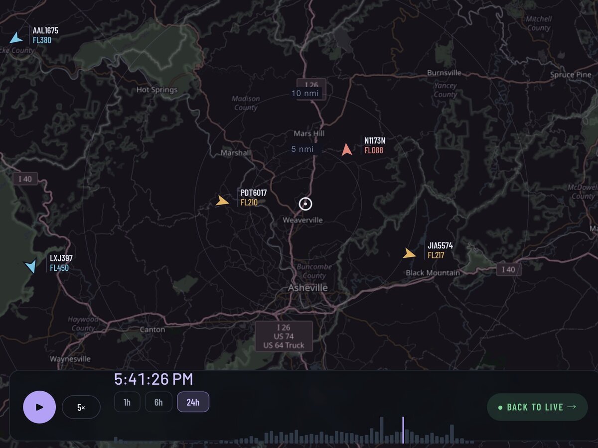 A dark map of the area around Asheville with range rings and several color-coded aircraft markers labeled with callsign and flight level, above a 24-hour replay timeline