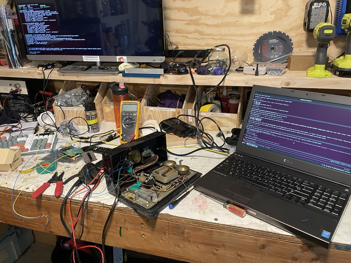 The rotary phone opened up on a workbench next to a laptop and monitor running pulse-decoding code
