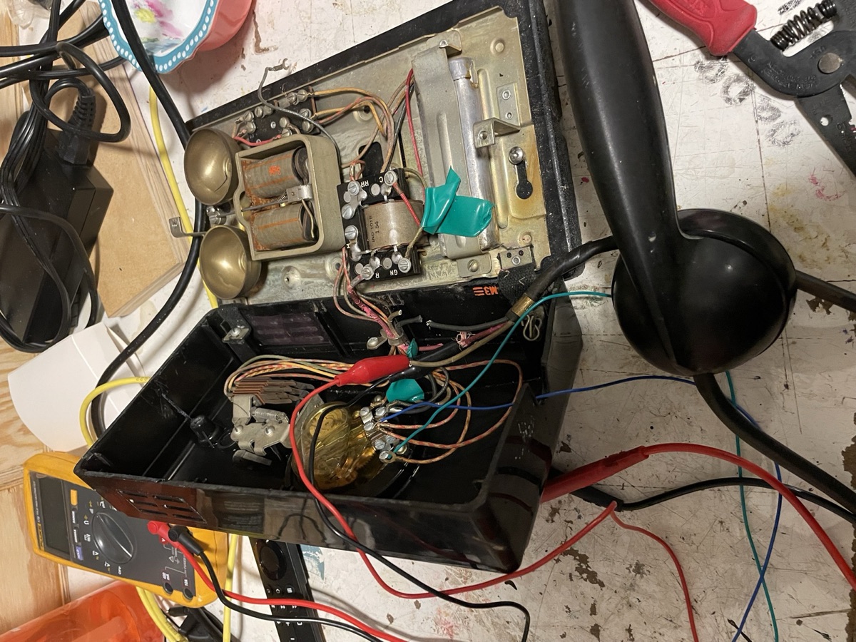 The open phone chassis with its bells and coils, wired up with alligator clips to a Raspberry Pi for testing